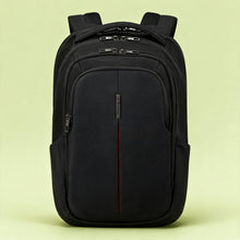 Load image into Gallery viewer, A black nylon backpack with multiple zippered compartments and padded shoulder straps, photographed against a solid pale yellow-green studio background.