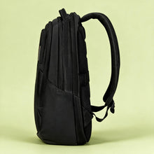 Load image into Gallery viewer, A black Maxmillian backpack with a textured front pocket, silver zippers, and a thin red vertical accent line, set against a solid pale yellow-green background.