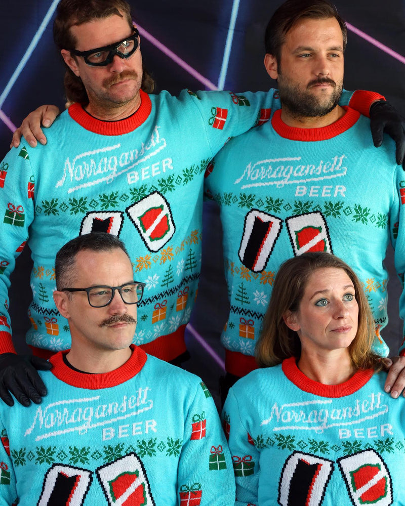 Four people posing together in matching turquoise custom Narragansett Beer knitted Christmas sweaters by Roody, featuring the Narragansett Beer logo and beer-can graphics, photographed against a dark background with neon lighting.