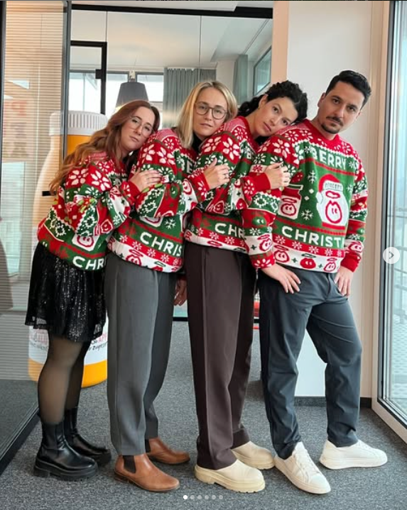 Custom Christmas Sweaters for Innocent Smoothies worn by 4 people in an office. Knitted sweaters - red, green and white - fun pose